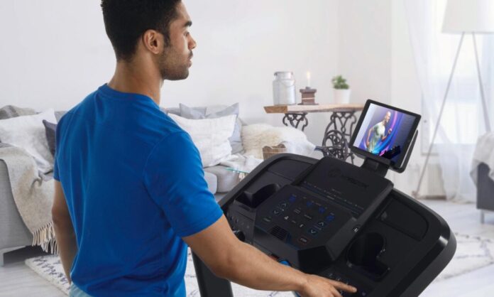 Użytkownik obsługujący bieżnię domową podczas treningu