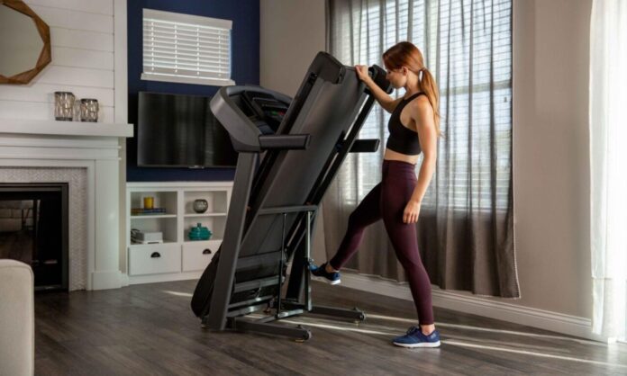 Kobieta składająca bieżnię w domu – cardio mity i trening w domu