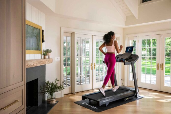 Kobieta biega w domu na bieżni Horizon 5.0 AT – trening w eleganckim wnętrzu
