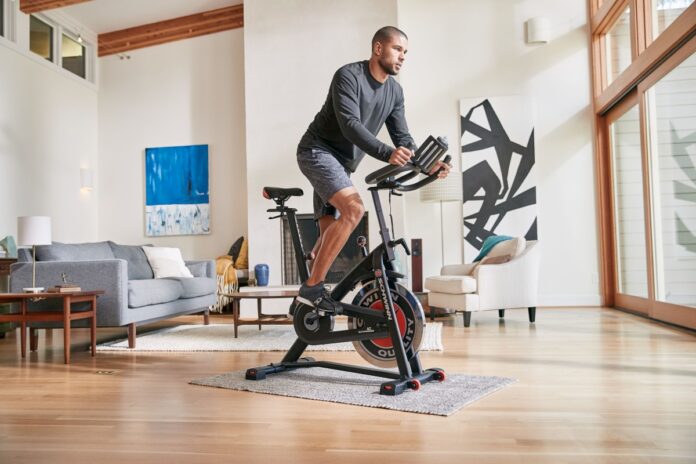 Mężczyzna trenujący na rowerku Schwinn IC3 w domowym salonie