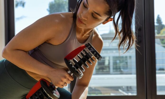 Trening z hantlami regulowanymi w domowej siłowni w piwnicy