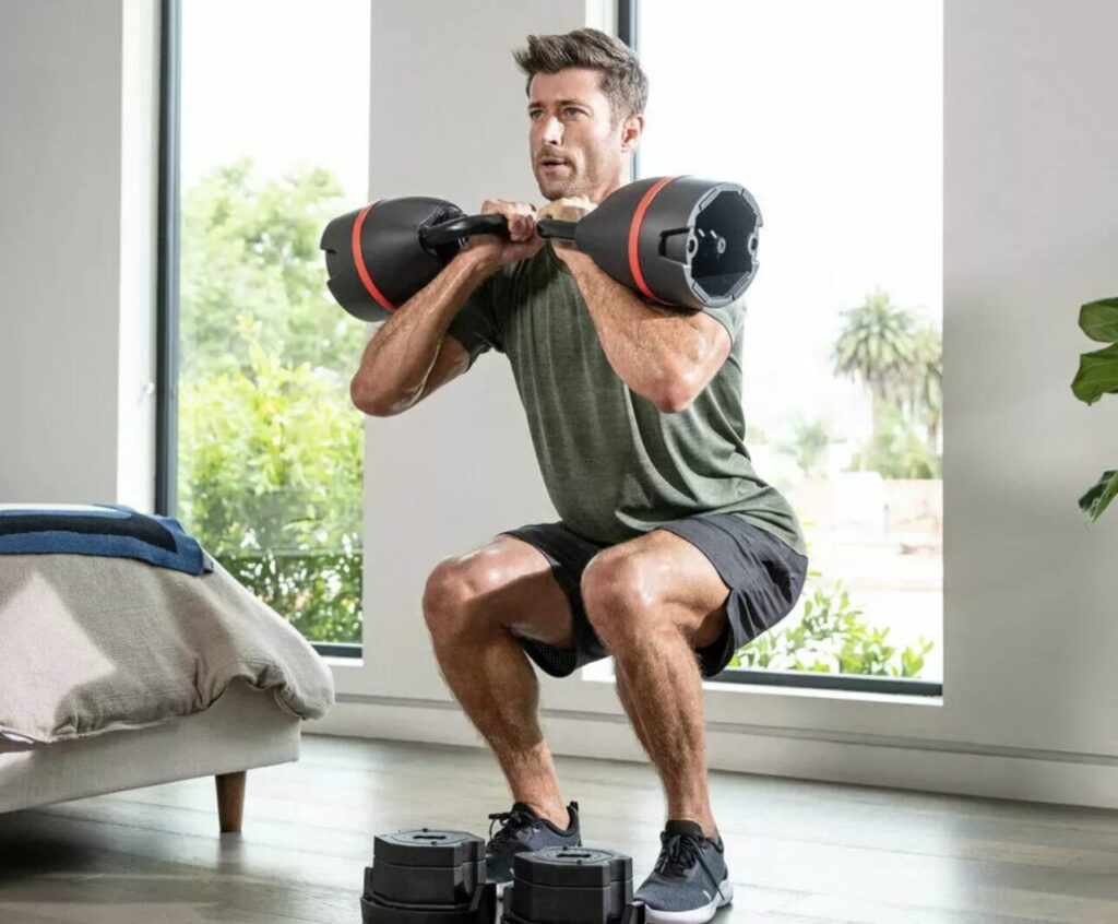 Mężczyzna ćwiczy z regulowanymi ciężarami Bowflex 