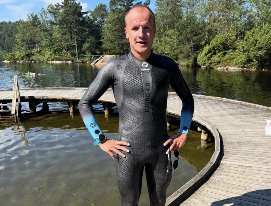 Triathlonista w piance deboer Fjord 4.0 stojący przy pomoście podczas treningu pływania w wodach otwartych