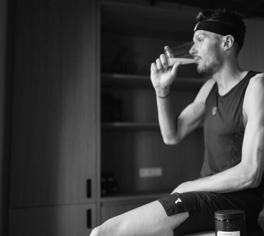 Triathlonista pijący suplement Pillar Performance Triple Magnesium wspierający sen i regenerację po treningu