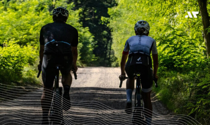 Dwóch kolarzy jedzie na rowerach gravelowych po leśnej drodze podczas treningu przed sezonem triathlonowym