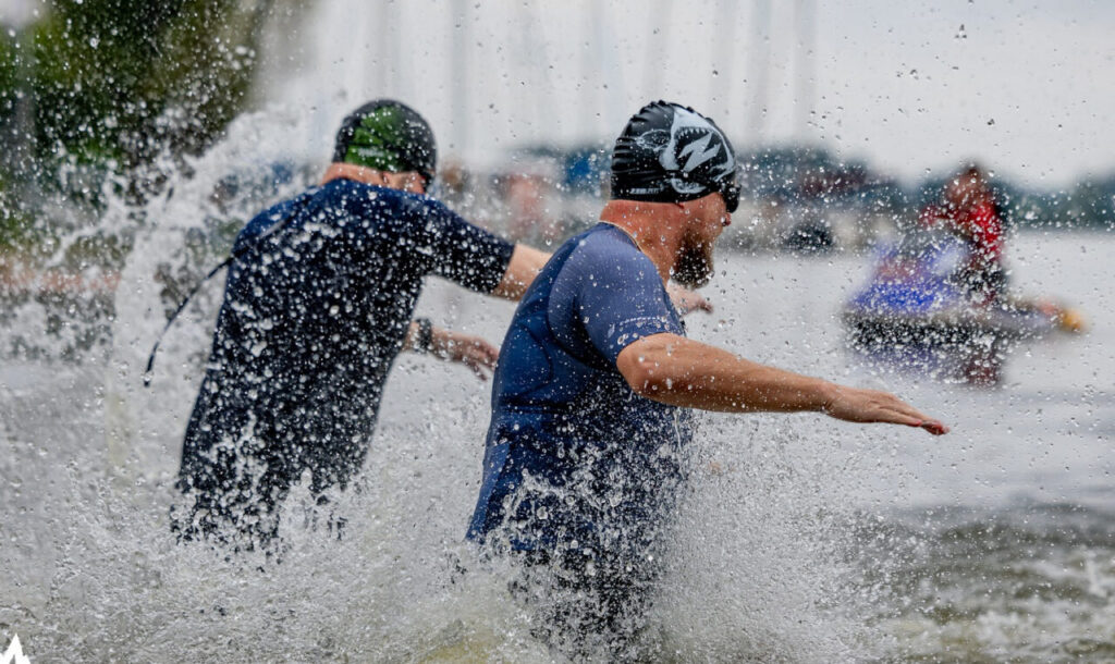 Zawodnicy rozpoczynający etap pływacki w wodach otwartych – stres i dynamika pierwszego startu w triathlonie.