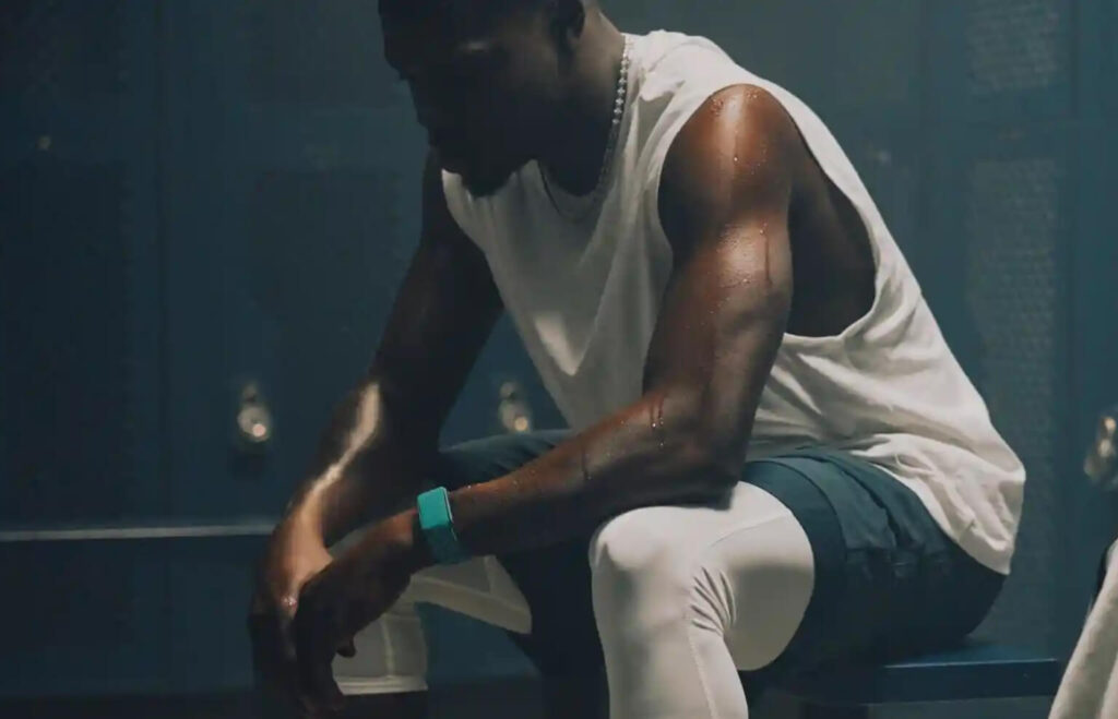 Brak progresu triathlon – przemęczony zawodnik po treningu siedzący w szatni, analiza regeneracji i obciążenia treningowego