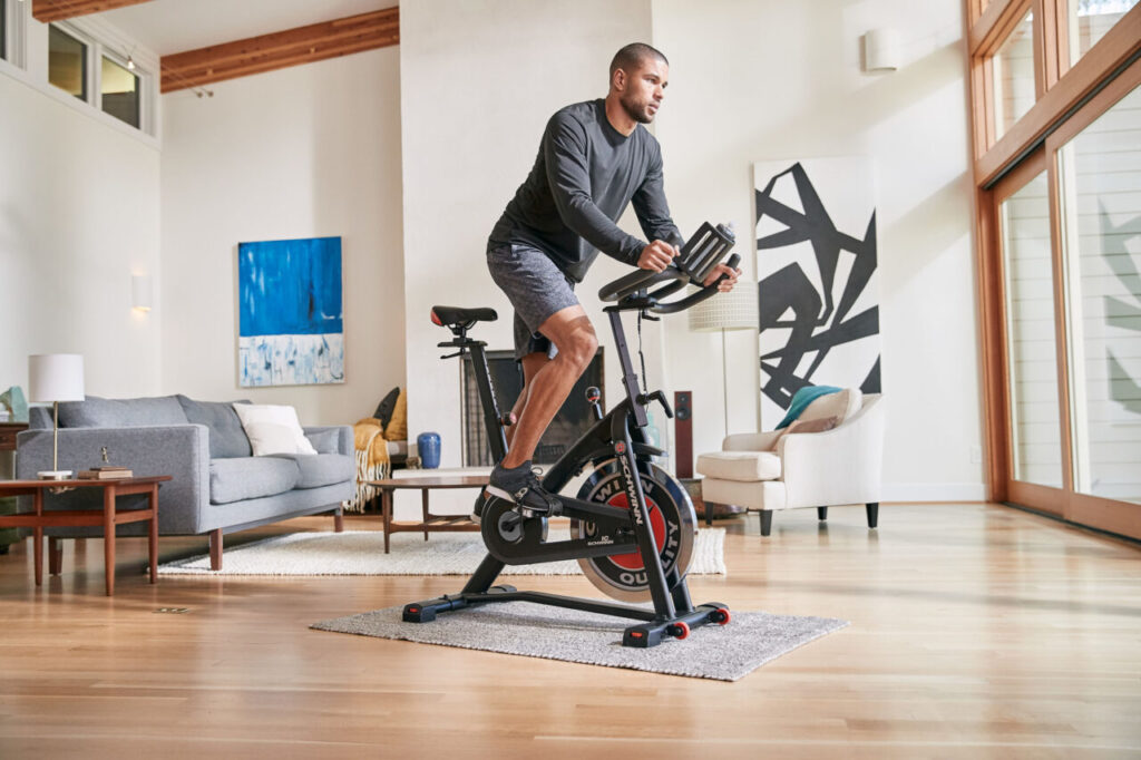 Mężczyzna trenujący na rowerze spinningowym w domu – trening cardio i spalanie kalorii podczas jazdy na spinningu
