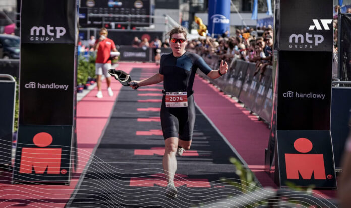 Zawodniczka triathlonu przekraczająca linię mety podczas zawodów IRONMAN Poland, finisz biegu wśród kibiców