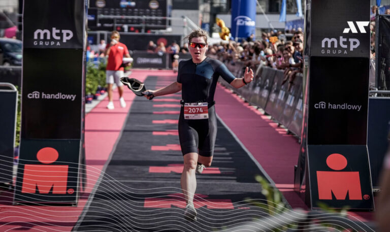 Zawodniczka triathlonu przekraczająca linię mety podczas zawodów IRONMAN Poland, finisz biegu wśród kibiców