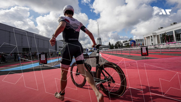 Zawodnik IRONMAN prowadzi rower w strefie zmian T1 podczas zawodów triathlonowych