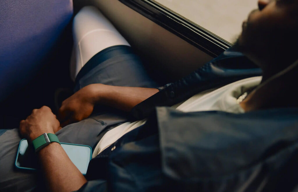 Triathlonista odpoczywający w podróży z opaską monitorującą sen i regenerację, kontrola parametrów organizmu między treningami.
