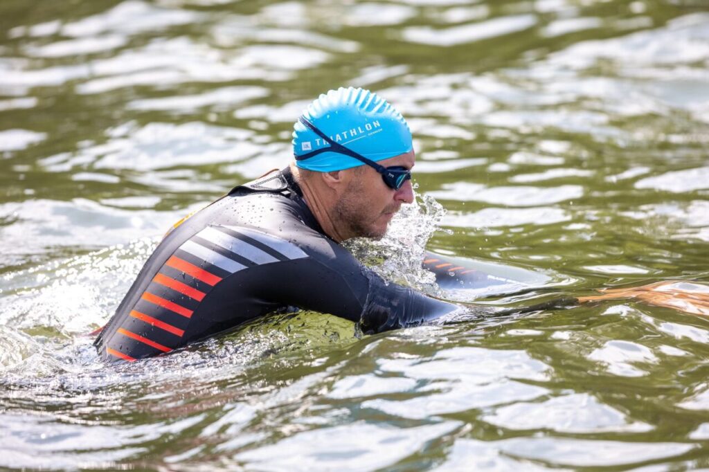Zawodnik w piance triathlonowej podczas pływania w wodach otwartych – przygotowanie pianki triathlonowej do sezonu startowego
