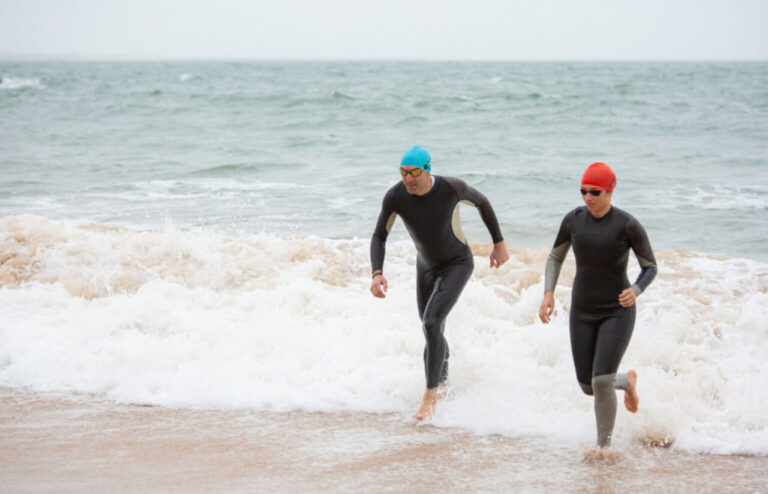 Zawodnicy wybiegający z wody podczas triathlonu – etap pływacki do analizy po słabszym wyniku.