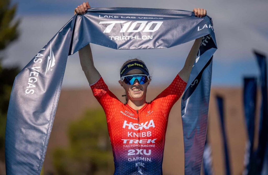Taylor Knibb świętuje zwycięstwo w zawodach T100 Triathlon w Lake Las Vegas, trzymając taśmę finiszera po wygranym wyścigu