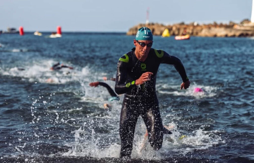 Triathlonista w piance podczas wyjścia z wody w trakcie zawodów – test pianki triathlonowej przed sezonem startowym w wodach otwartych
