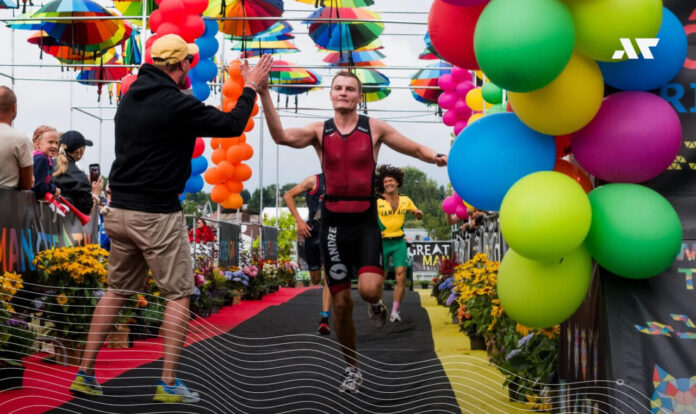 Zawodnik przekraczający linię mety i przybijający piątkę kibicowi podczas zawodów triathlonowych, wyraźna radość i satysfakcja po starcie