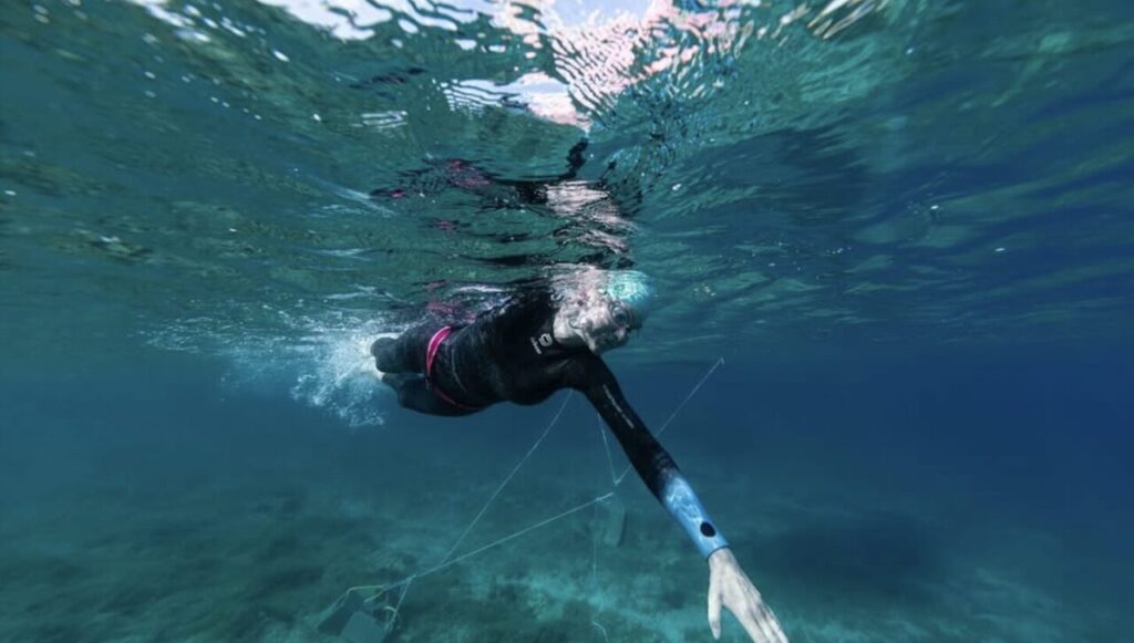 Triathlonista płynący w piance triathlonowej podczas treningu w open water 