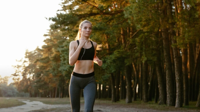 Zawodniczka biegnąca w lesie podczas spokojnego treningu biegowego jako element powrotu do formy po starcie w triathlonie.