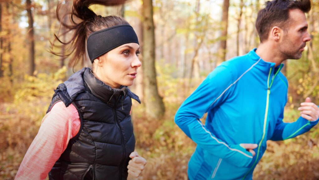 Kobieta i mężczyzna podczas treningu biegowego w lesie, przygotowanie biegowe do triathlonu.
