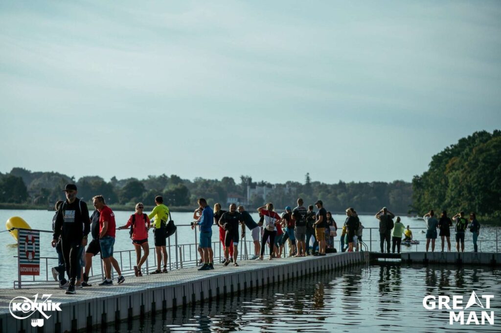 Zawodnicy i kibice przed startem triathlonu nad jeziorem